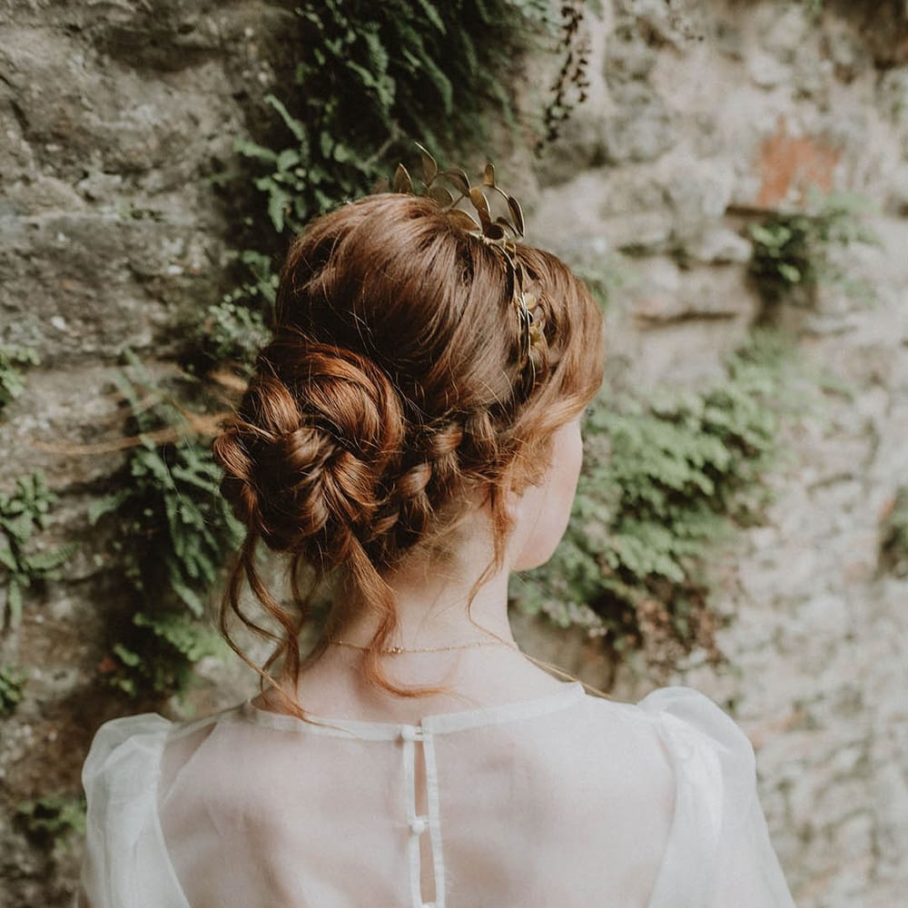 Bride with wearing a wedding dress with sheer top layer with buttons and long sleeve with a chic wedding hairstyle 