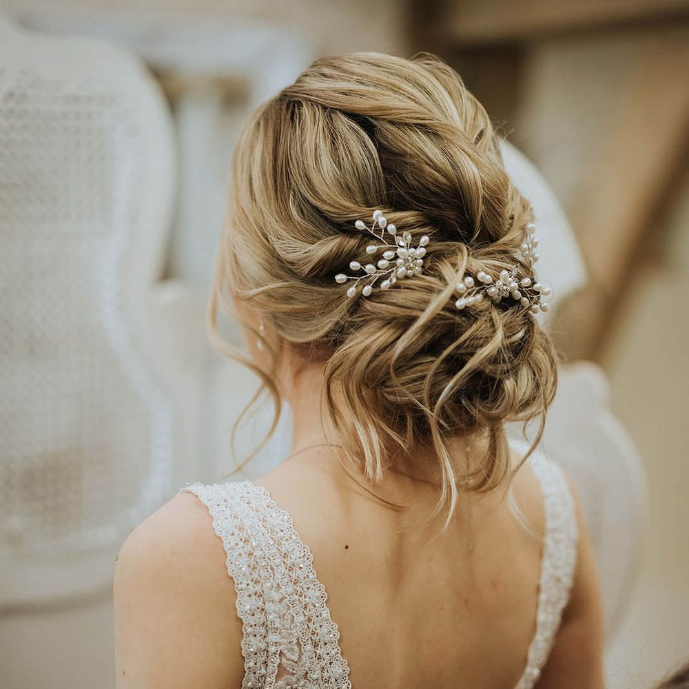 Bride with blonde hair in an updo with a pearl and silver floral wedding hair accessories
