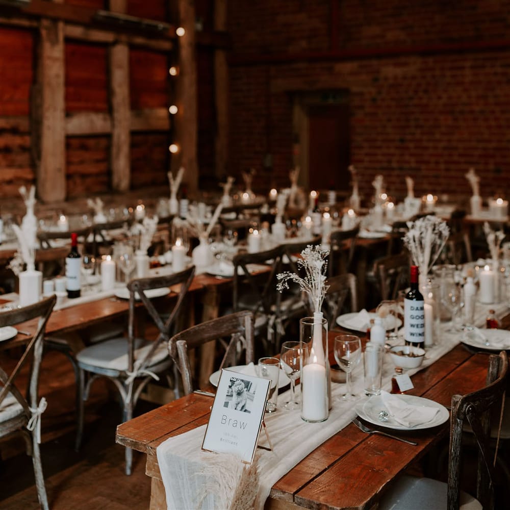 Pimhill Barn wedding venue with a simple and neutral wedding tablescape with white pillar candles, white table runners and dried flowers with pampas grass
