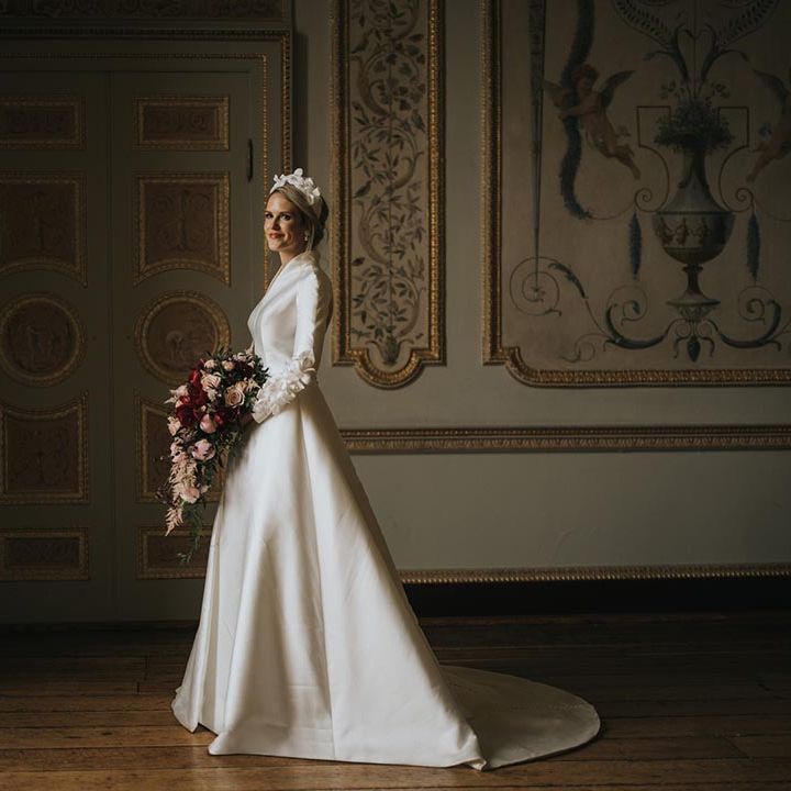 Bride in traditional and conservative Jesus Peiro wedding dress with a floral hair piece and cascading bouquet