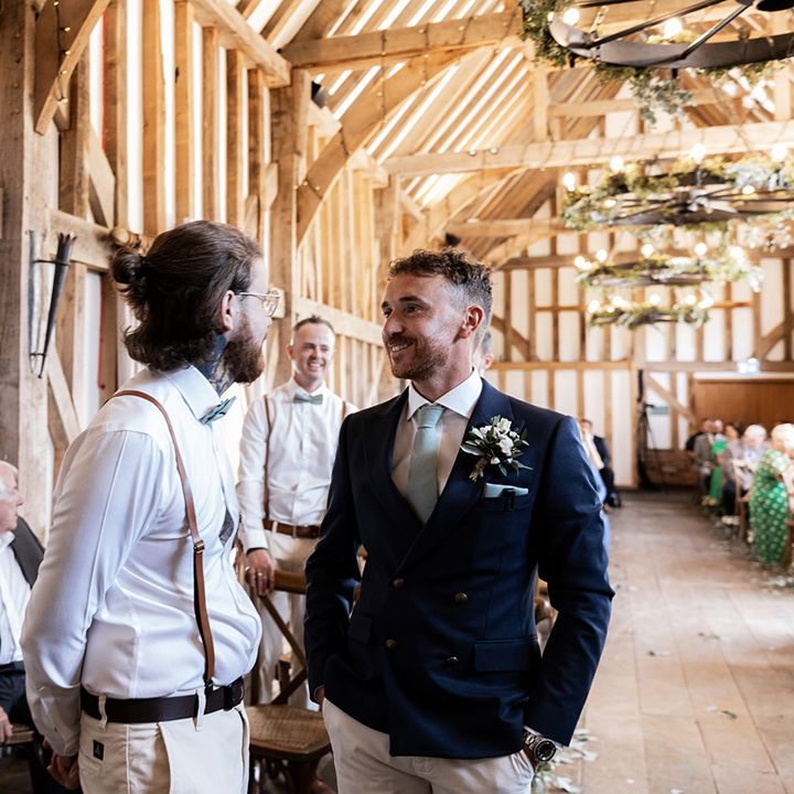Groom wears fitted blue jacket with pale blue tie and white floral buttonhole 