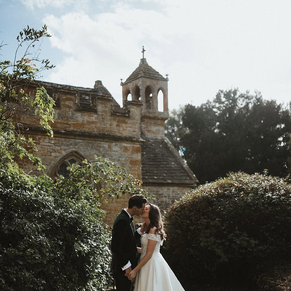The bride and groom share an intimate kiss as they share a moment alone together for their classic and timeless wedding 