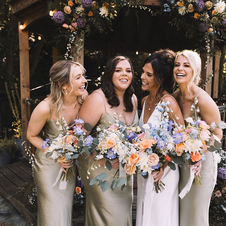 Pastel wedding theme for botanical wedding with the bridal party holding pastel wedding bouquets in sage green satin bridesmaid dresses 