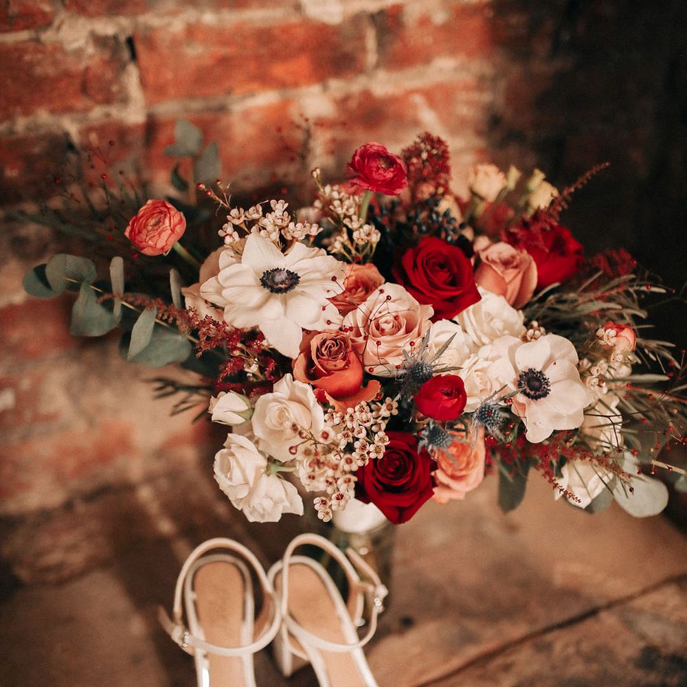Sparkly white wedding shoes with red and white wedding bouquet with white anemones 
