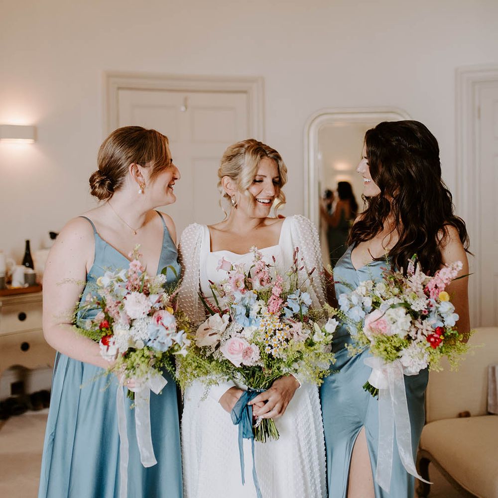 Bridesmaids wearing pale blue satin bridesmaid dresses with the bride in a long sleeve wedding dress 