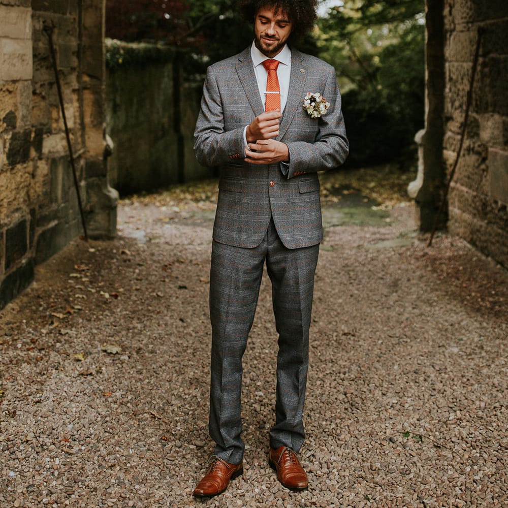 Groom in grey check suit with orange strip and wedding tie 