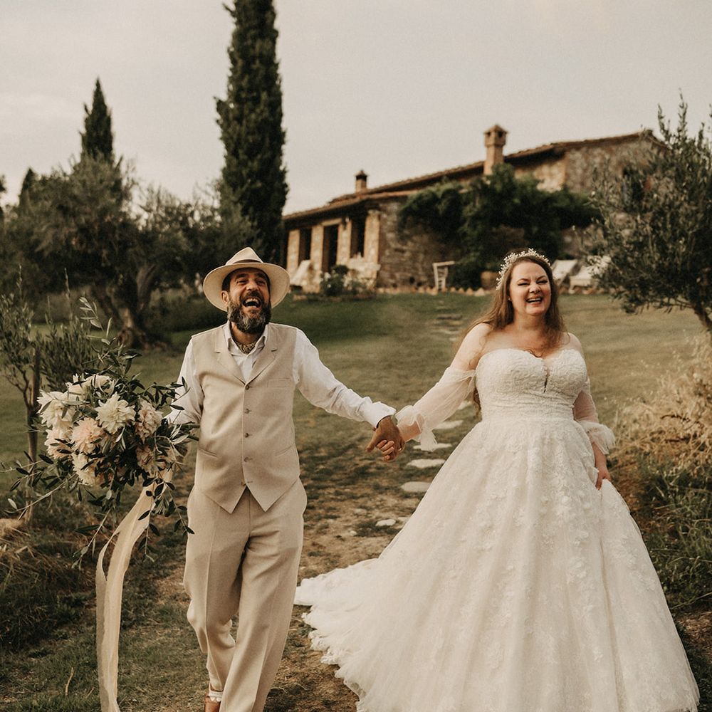 Bride and groom walking through Tuscany with olive bouquet