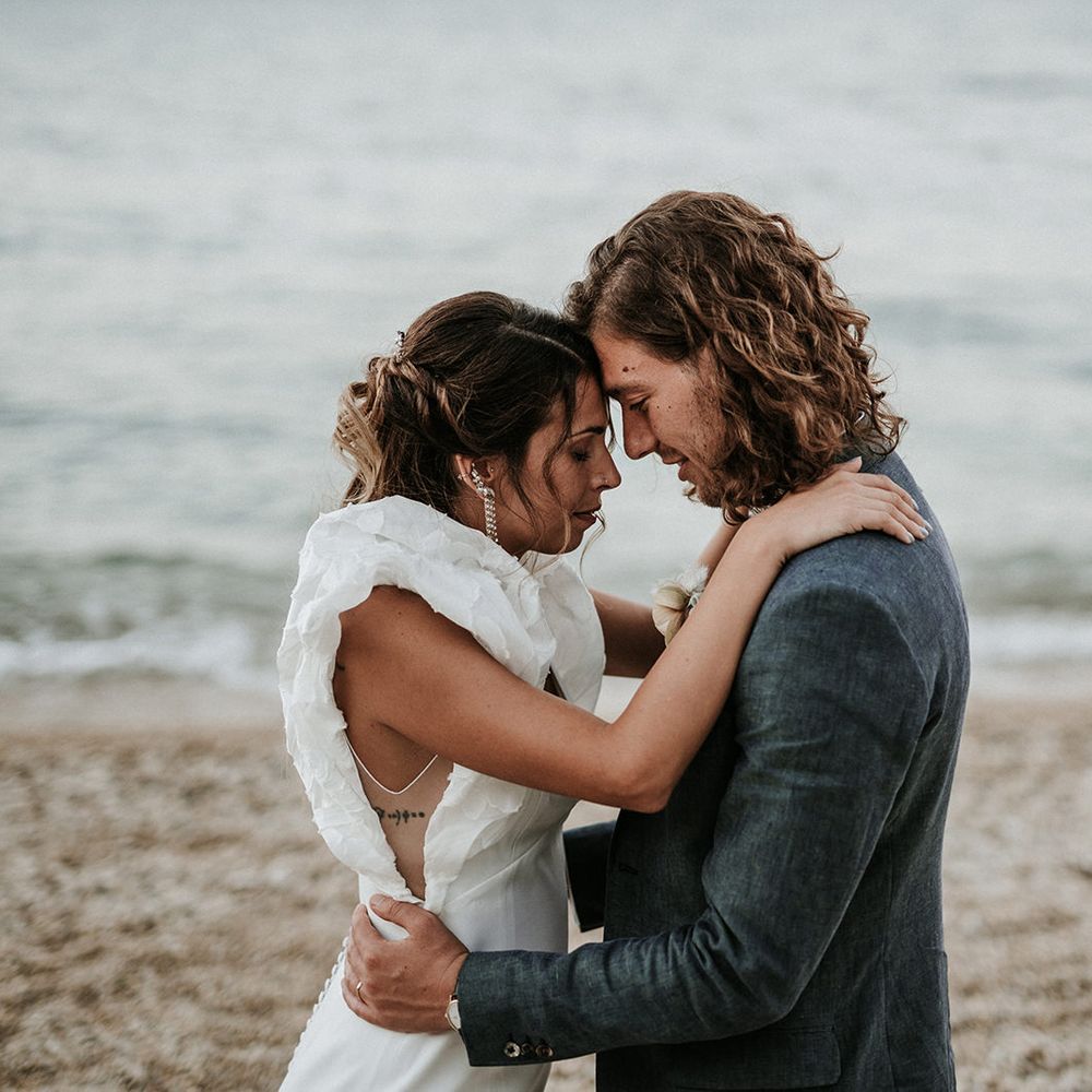 Bride in Rime Arodaky wedding dress with sheer panel side detail and ruffle sleeves on the beach with her husband in Italy 