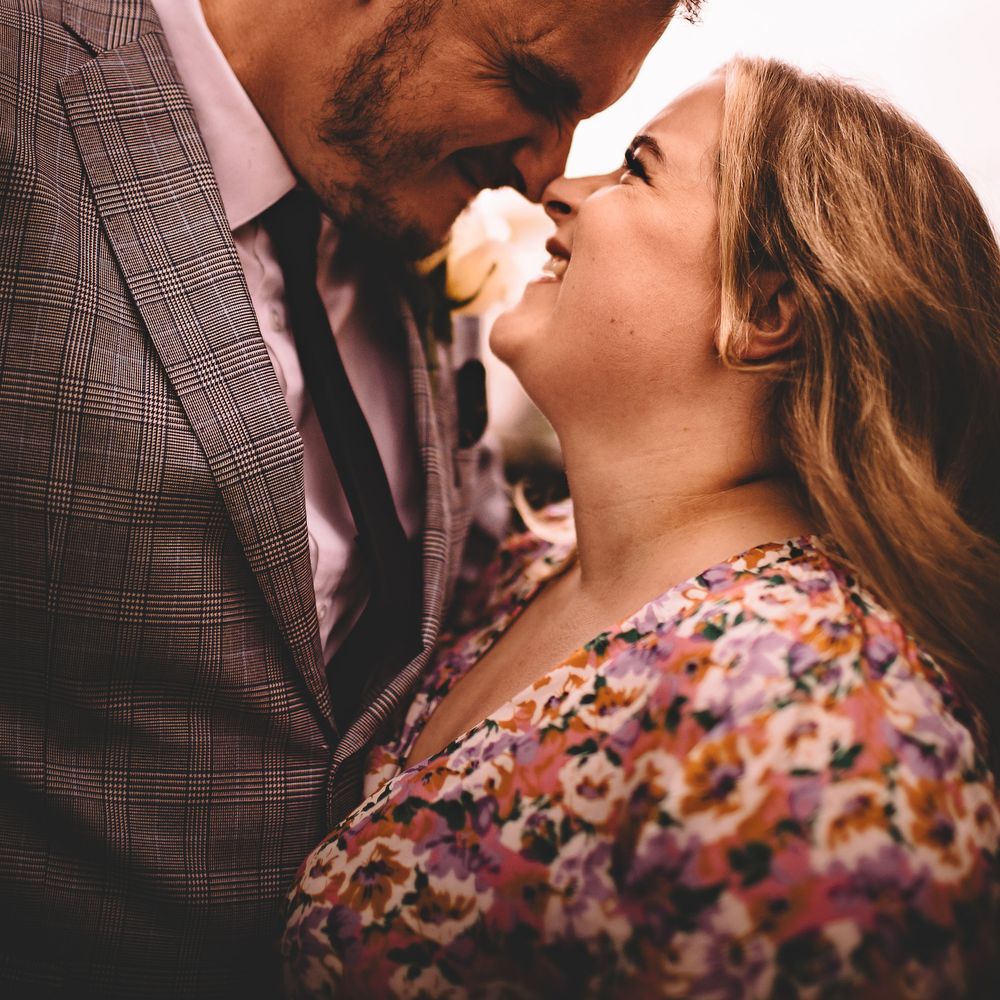 Bride & groom smile and laugh lovingly whilst looking at one another