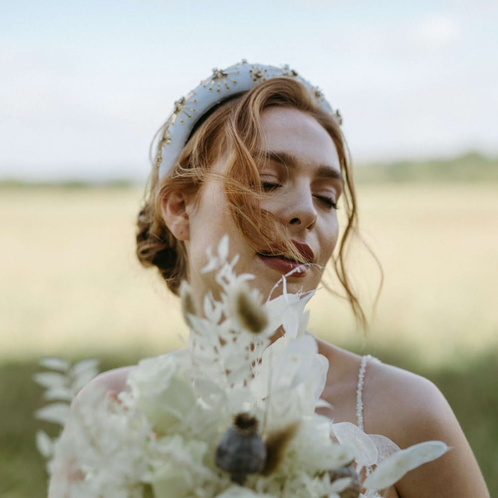 Bride wearing a white and gold beaded headband with all white flower bouquet