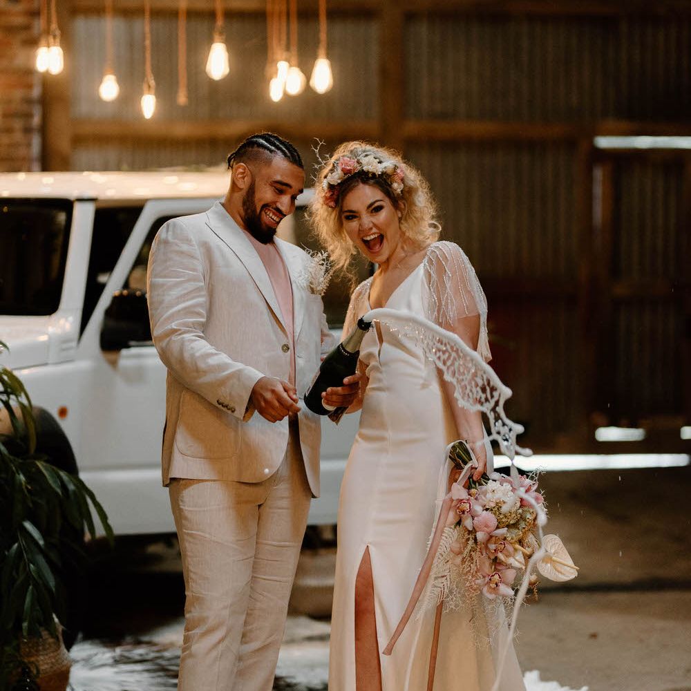 Bride and groom spraying a bottle of champagne