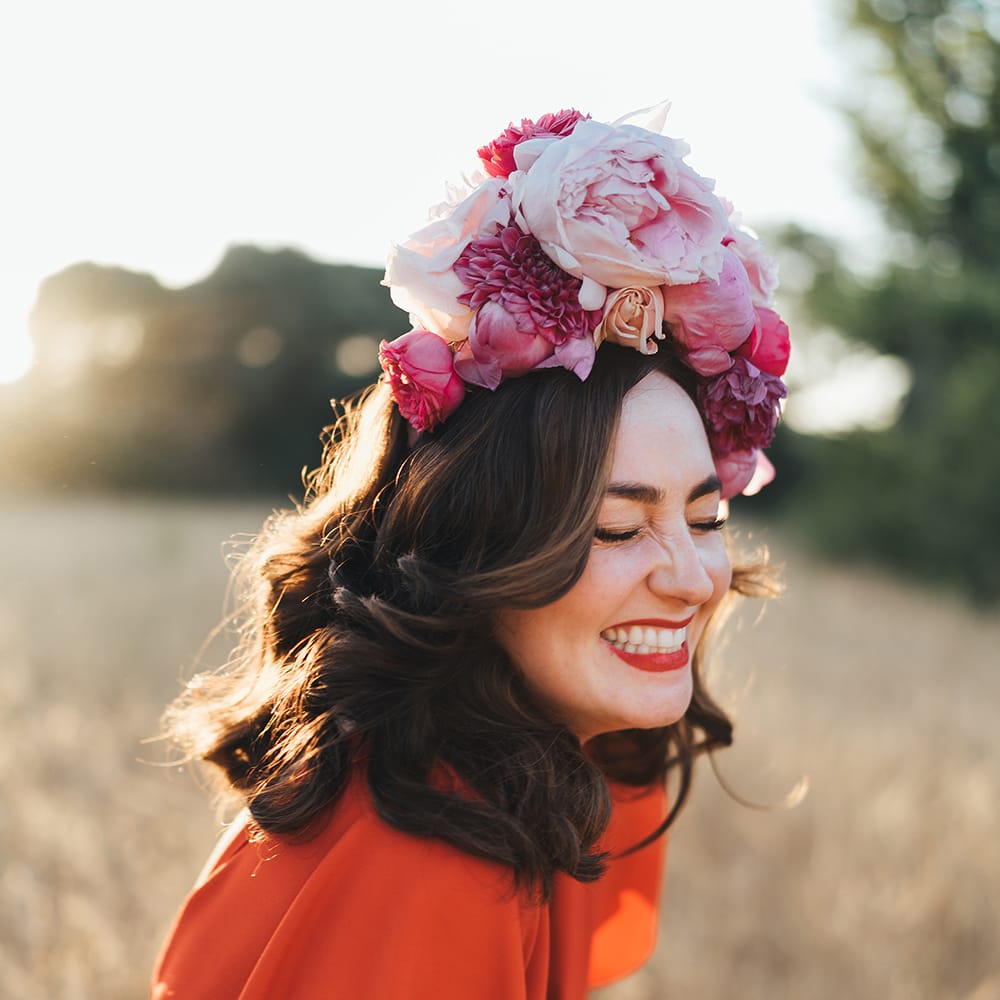 Bride wears her dark hair in curls and with a pink floral crown