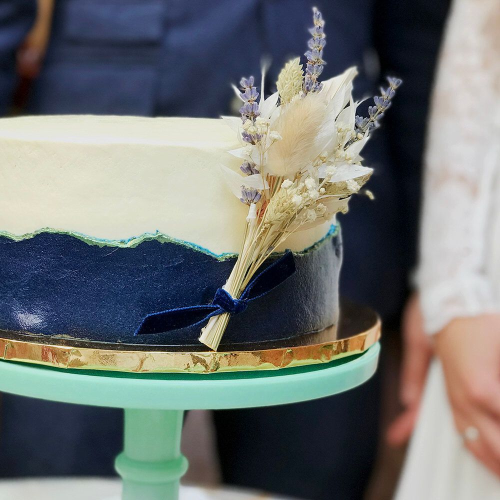 Dried flowers tied to side of white and navy wedding cake