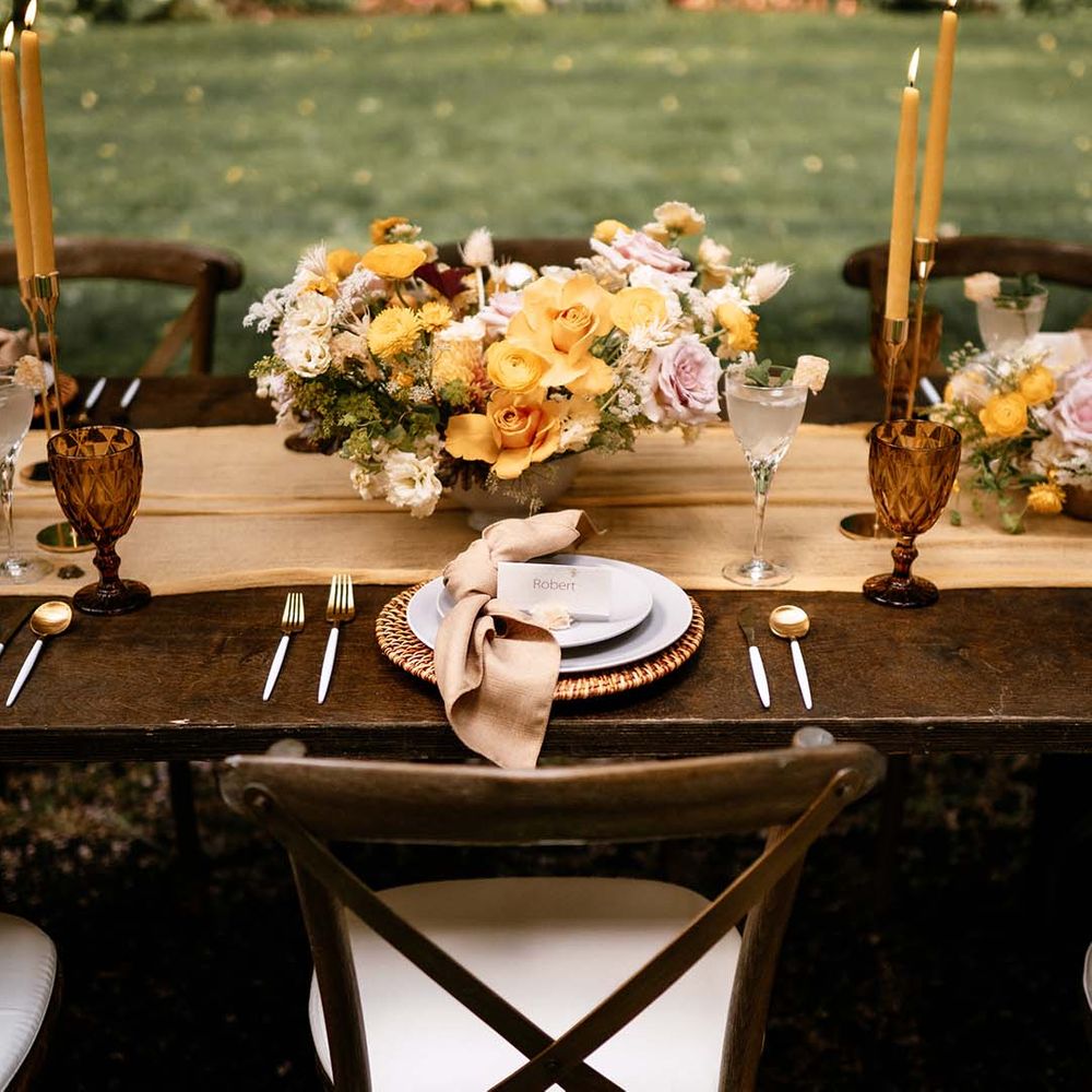 Honey yellow wedding inspiration with yellow flowers, gold candlesticks and wicker place mat table decor 