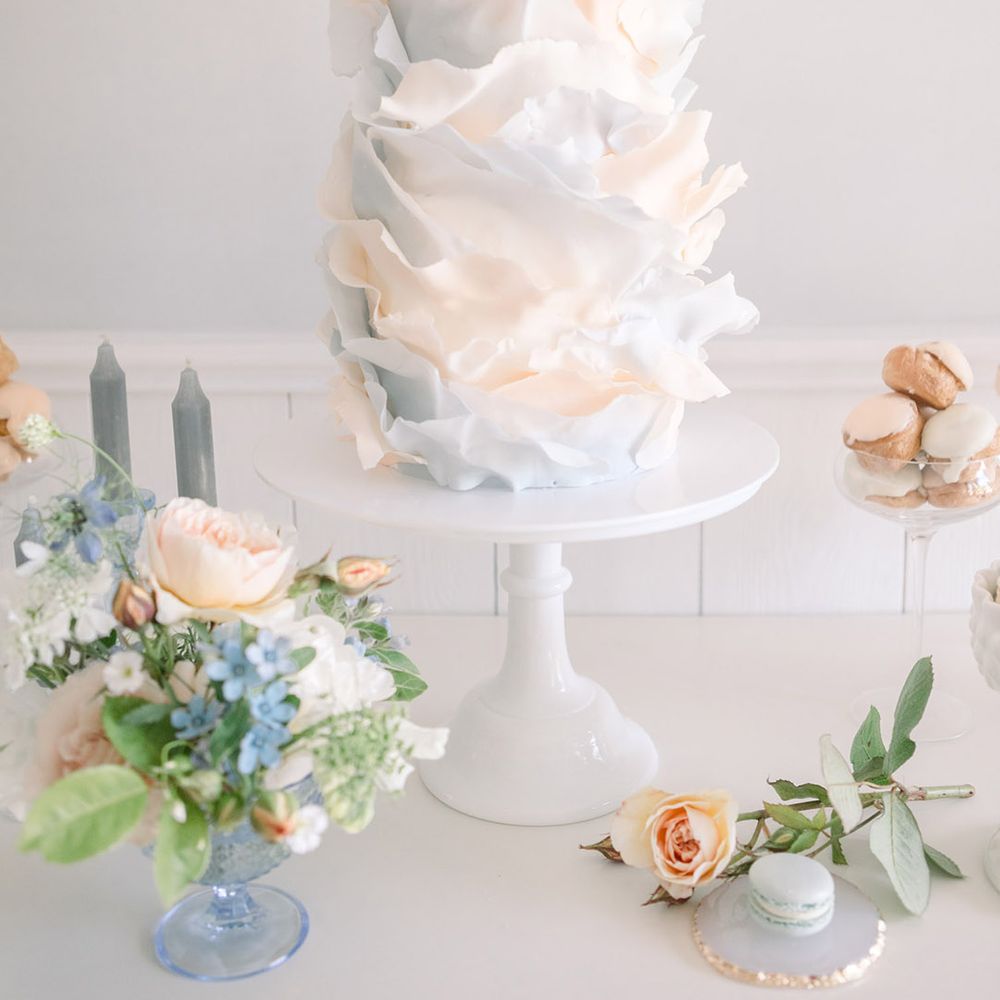Ombre peach and blue three tier ripple effect iced wedding cake on a white cake stand