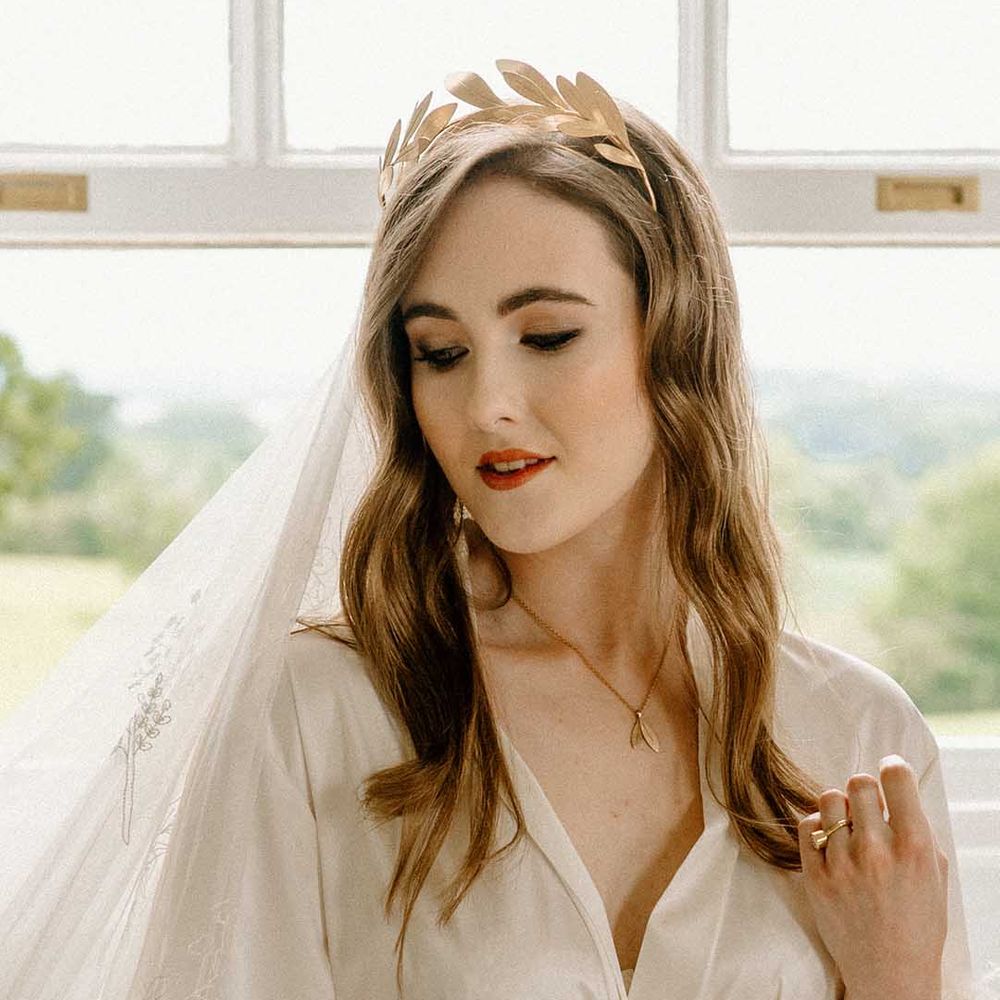 Bride in a wheelchair on the wedding morning in a getting ready robe with feather cuff detail, lace veil and gold crown headdress
