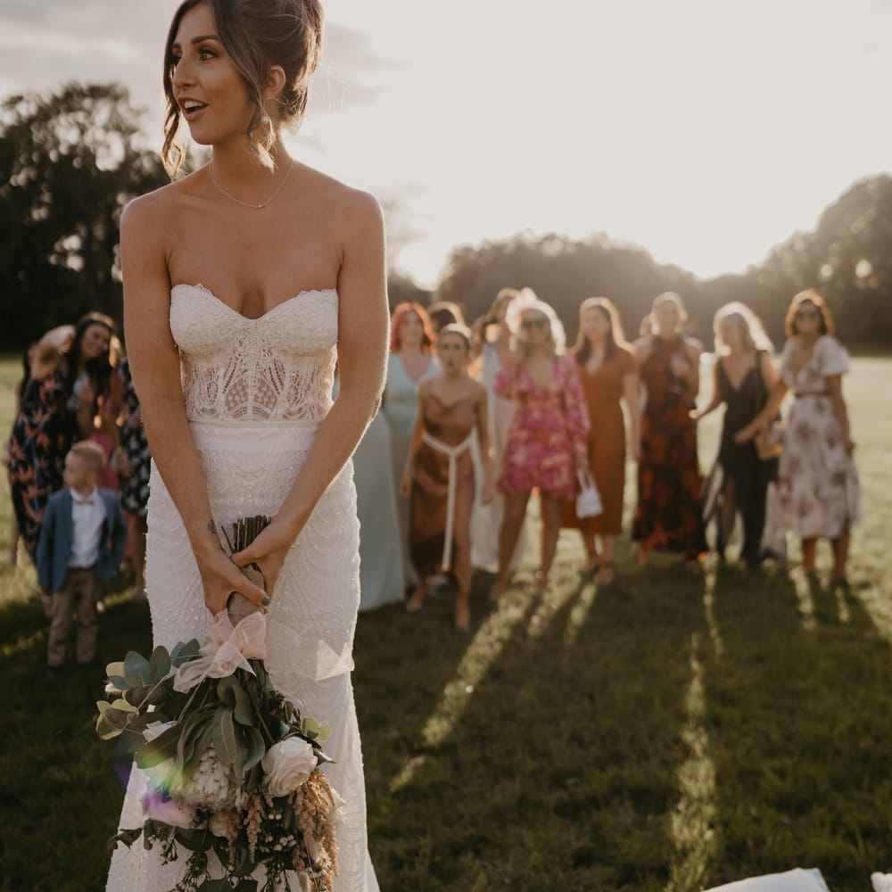 Bride prepares to throw her bouquet as wedding guests stand behind her at Duddon Mill Farm | Mark Bamforth Photography
