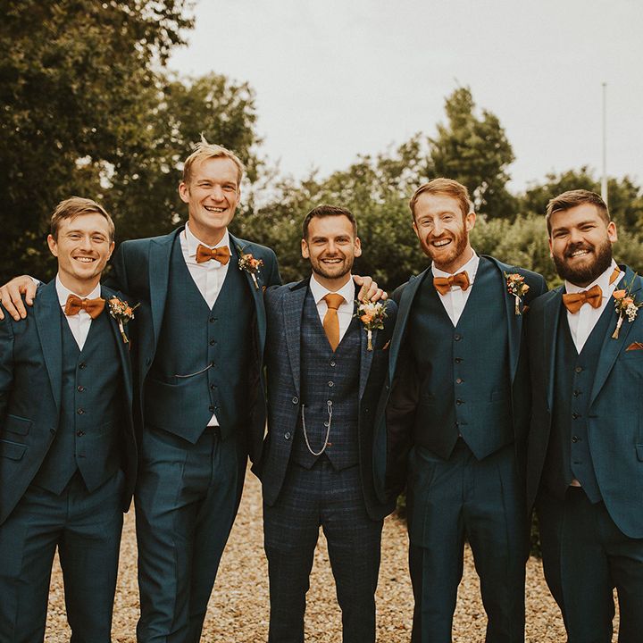 Groomsmen in matching blue suits with orange ties