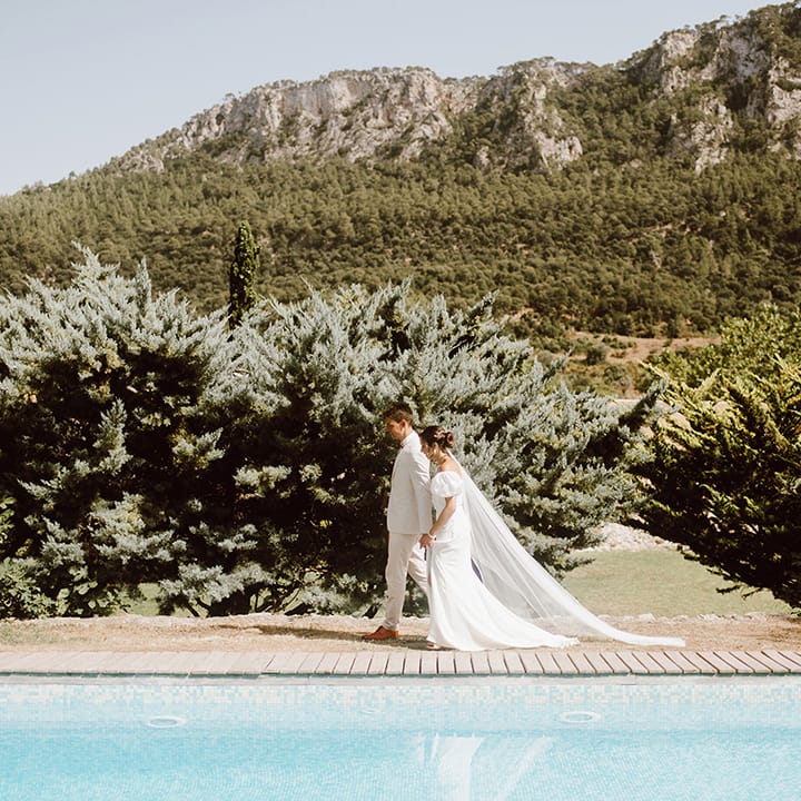 Bride and groom walking next to swimming pool