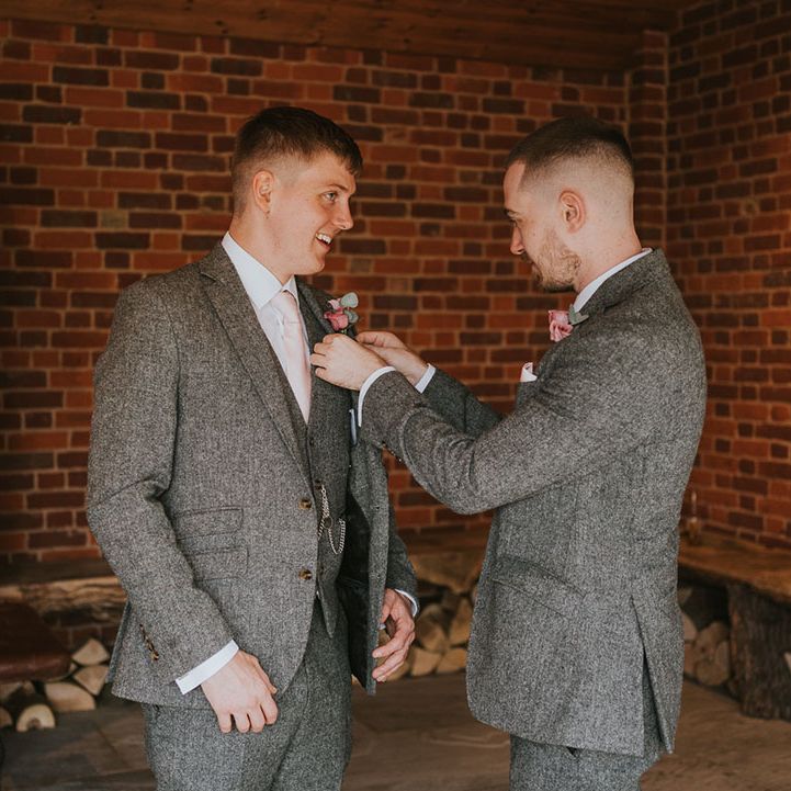 Groom and groomsman in matching grey tweed suits and pink rose boutonnières
