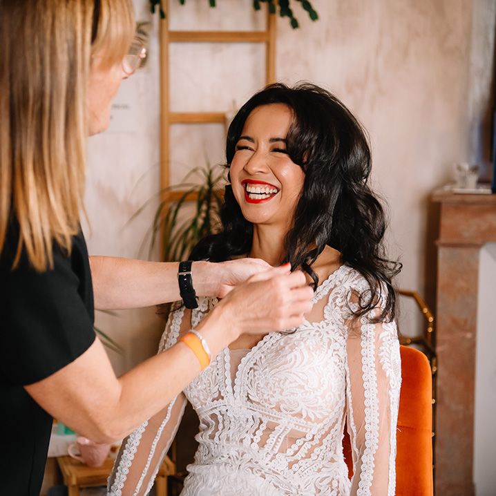 Bride in lace wedding dress with red lip gets hair done for the wedding day 