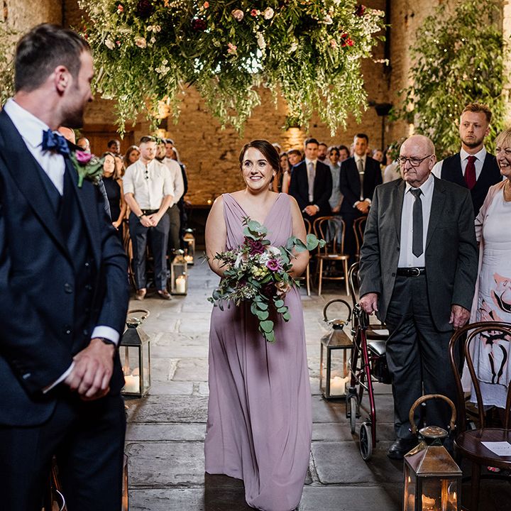 Bridesmaid in pale pink dress walks the down aisle for wedding 