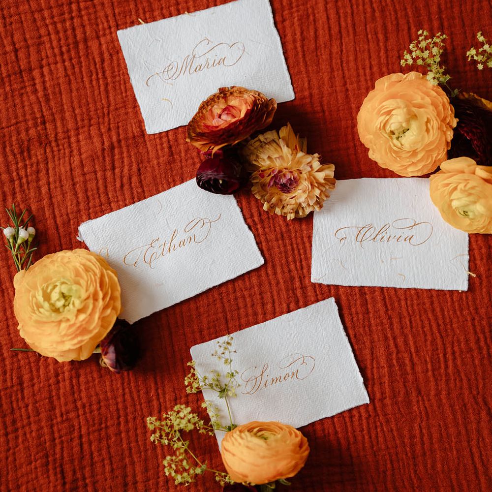 Name place cards written in gold calligraphy