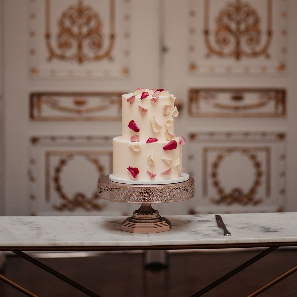 Two tier white wedding cake with light pink and dark pink rose petal decor 