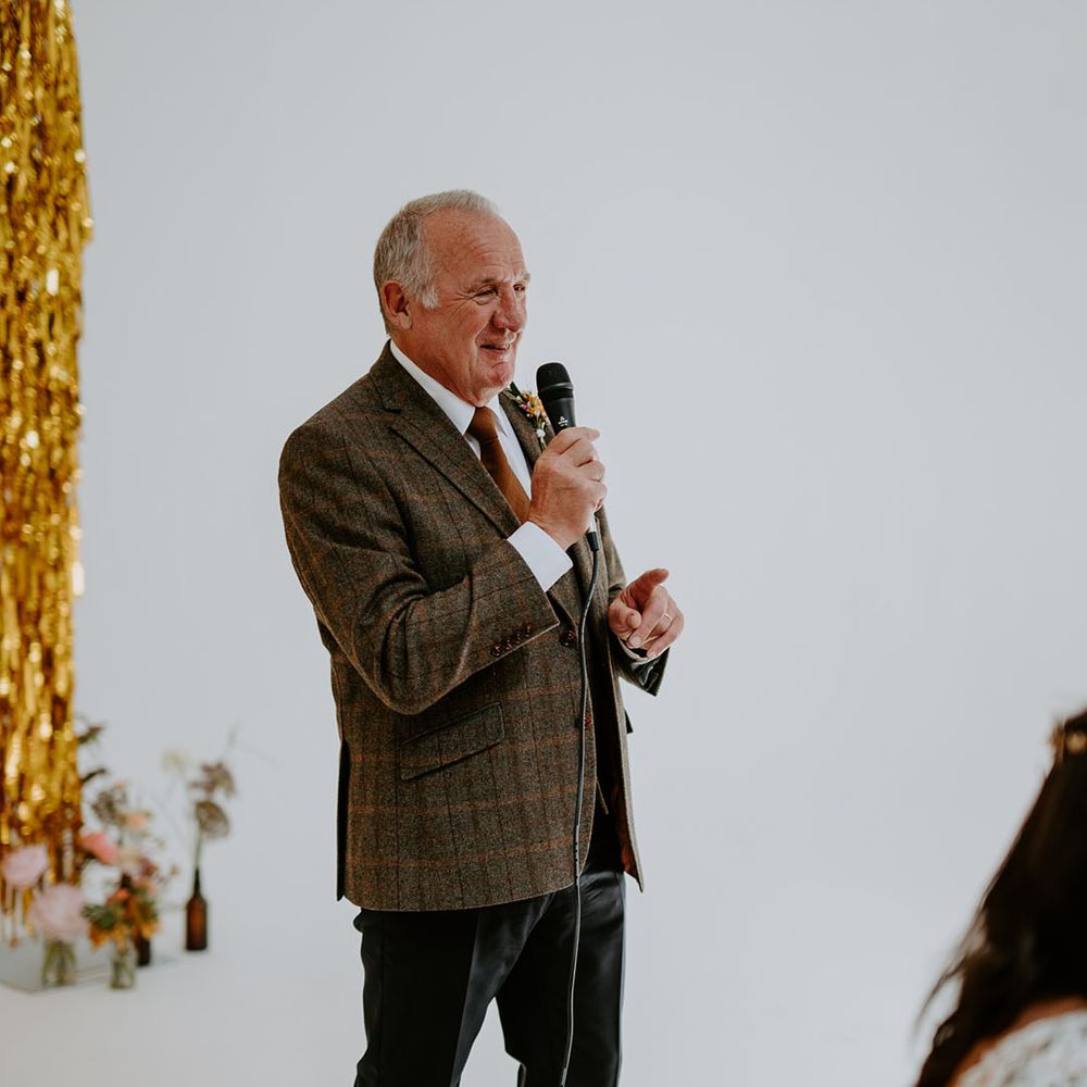 Wedding guest gives speech during reception at industrial styled wedding