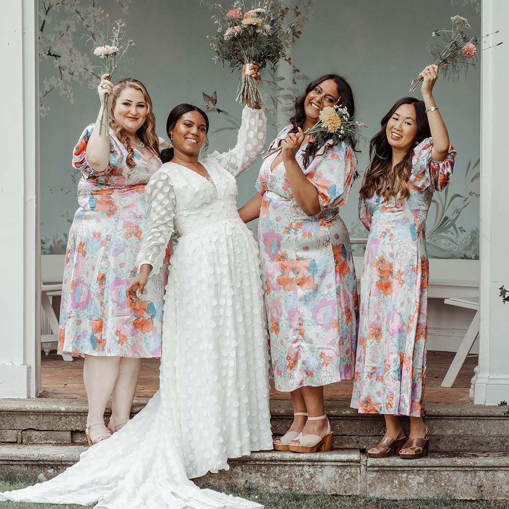 Bride in polka dot detailed appliqué wedding dress and bridesmaids in matching floral dresses at Wasing Park