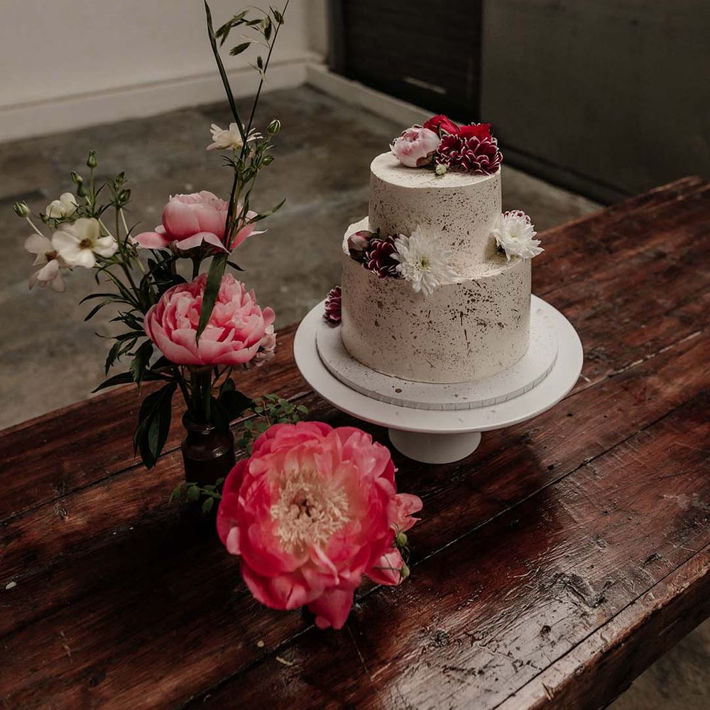 Cream two tiered spotted wedding cake with pink and white flower decorations