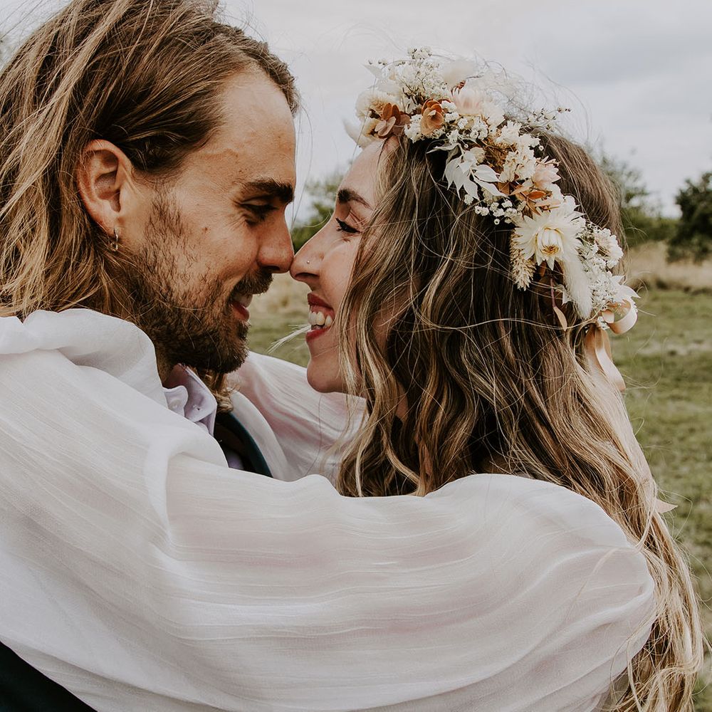Bride wears floral crown and embraces her groom outdoors on their wedding day
