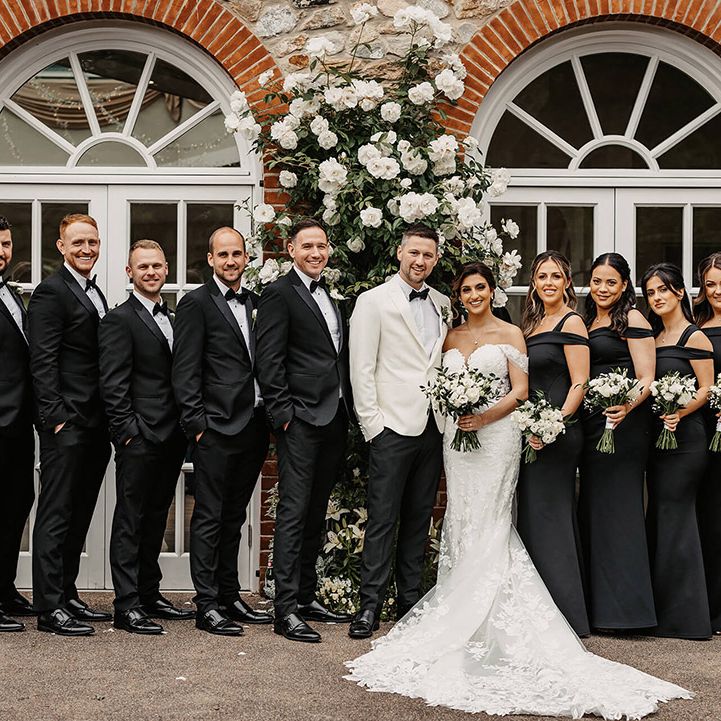 Monochrome wedding party with the bridesmaids in black one shoulder dresses and the groomsmen in black tie for the traditional wedding 