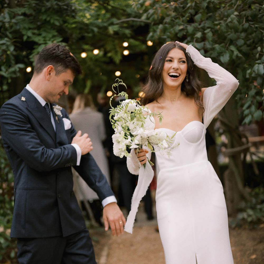 The bride and groom smile together as they brush off the confetti for their rustic wedding