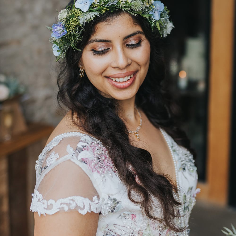 British Indian bride with natural makeup in a floral wedding dress wearing a flower crown 