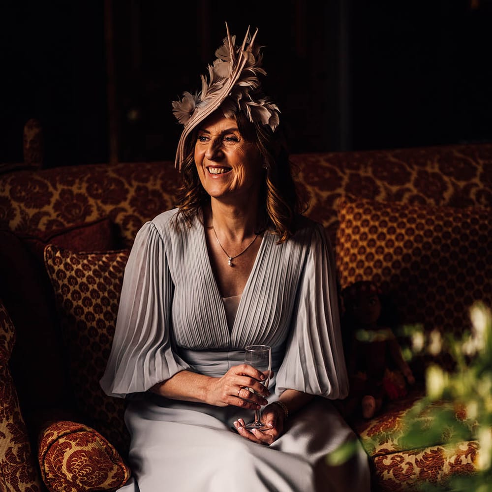 Wedding guest in pleated light blue dress with intricate pink feather hat