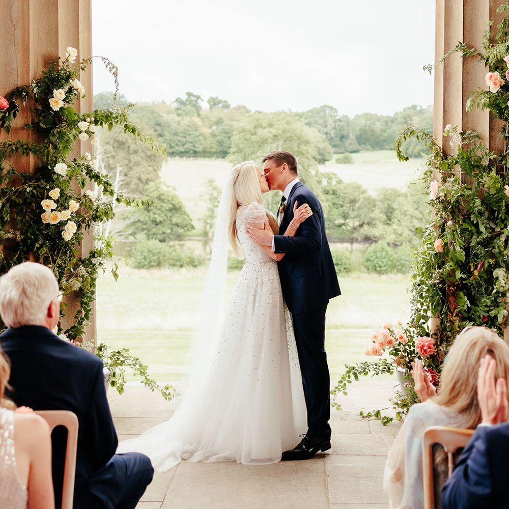 The bride and groom share their first kiss as a married couple at their outdoor wedding ceremony 