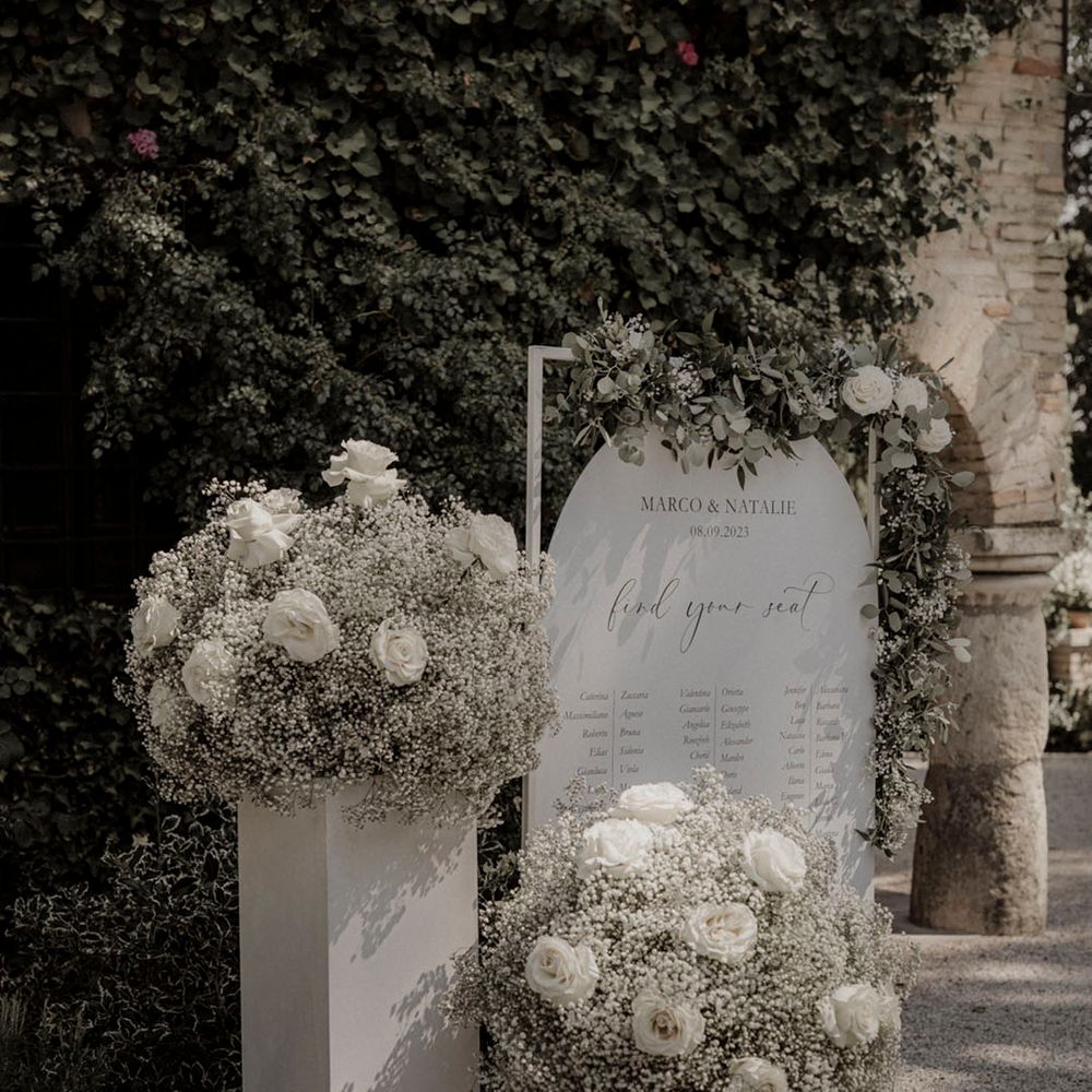 White roses and white gypsophila with white wedding table plan signage 