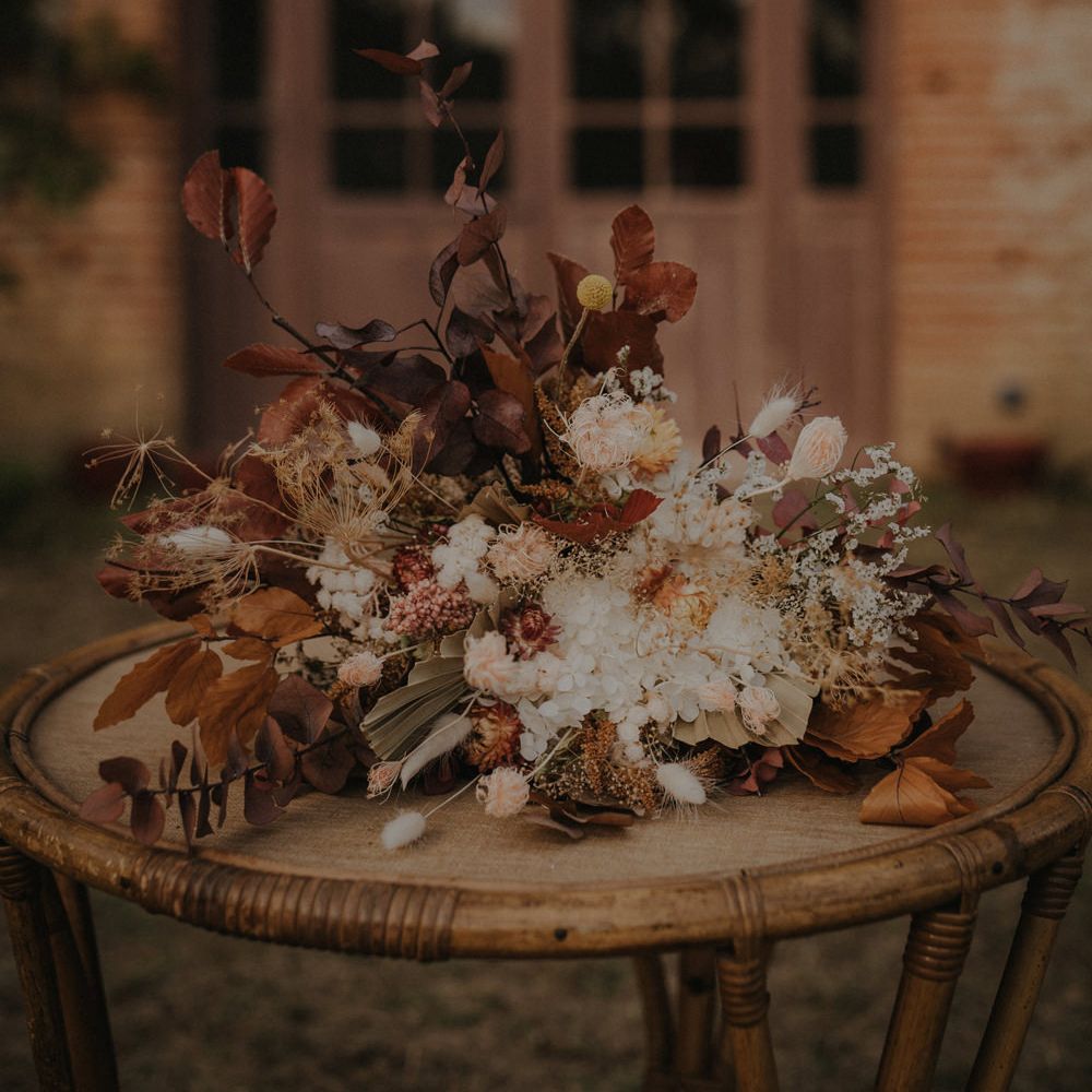 Autumn wedding bouquet with brown leaves, white flowers and foliage 