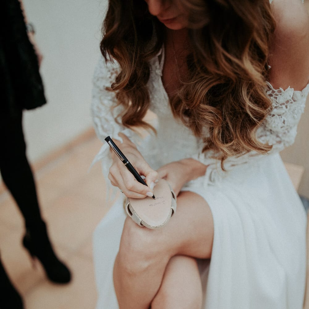 The bride writing on the bottom of her wedding heel