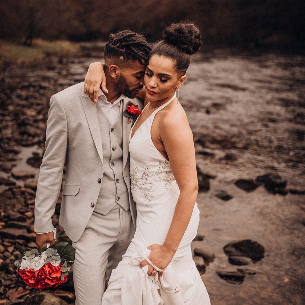 Bride & groom stand outside whilst groom wears grey suit