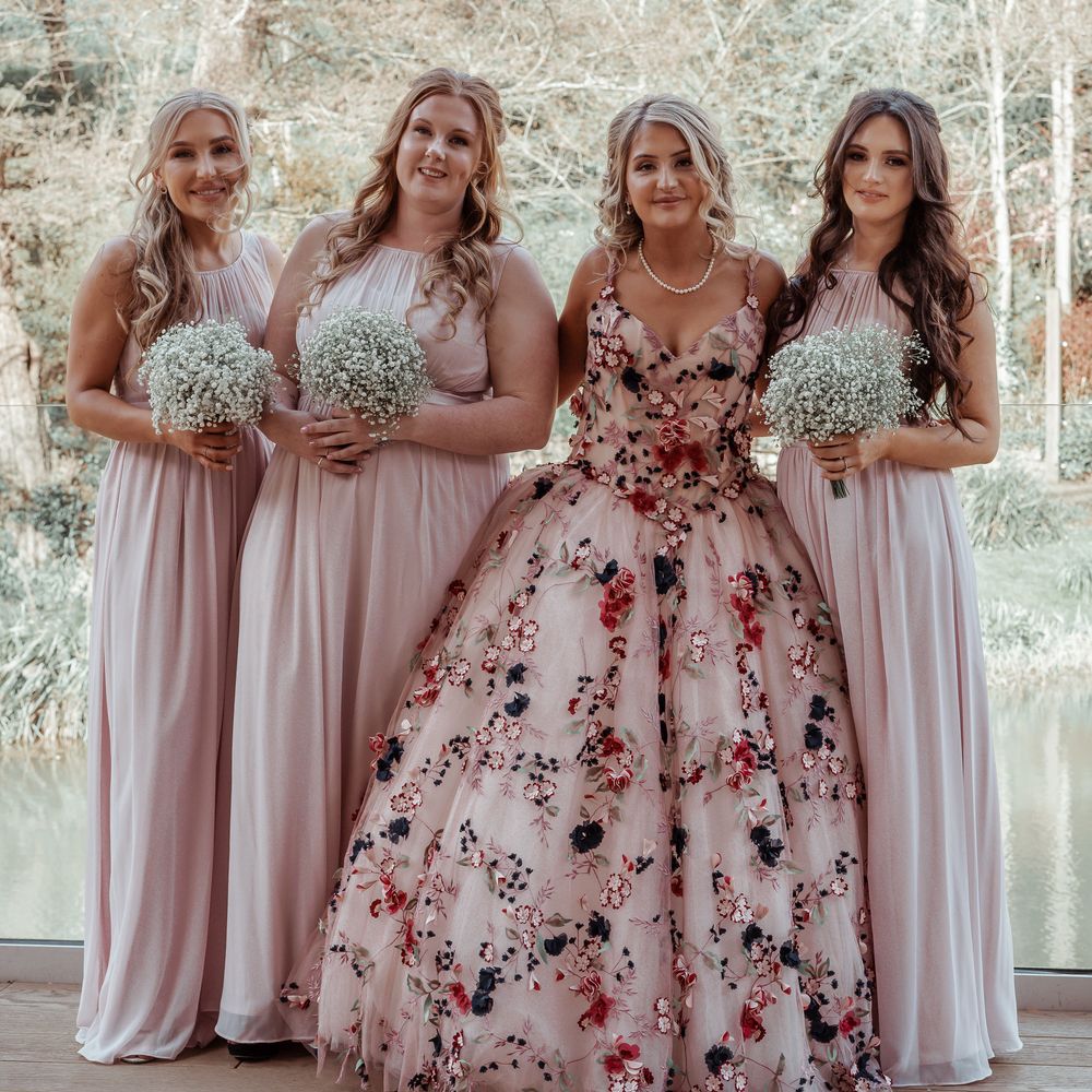 Bride stands with bridesmaids wearing blush pink bridesmaids dresses