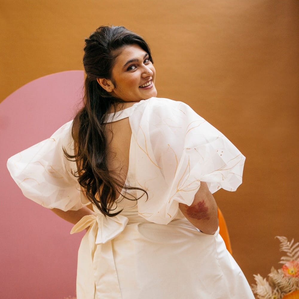 Bride looking back to the camera and smiling, showing off open back and bow detail of wedding separates