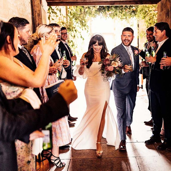 Groom in a check blue suit and bride in a strapless wedding dress with detachable sleeve and front split 