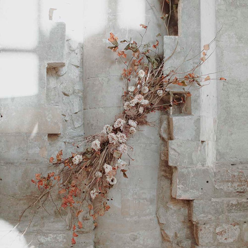 Minimalist wedding flower arrangement with twigs, vines, foliage and dried flowers 