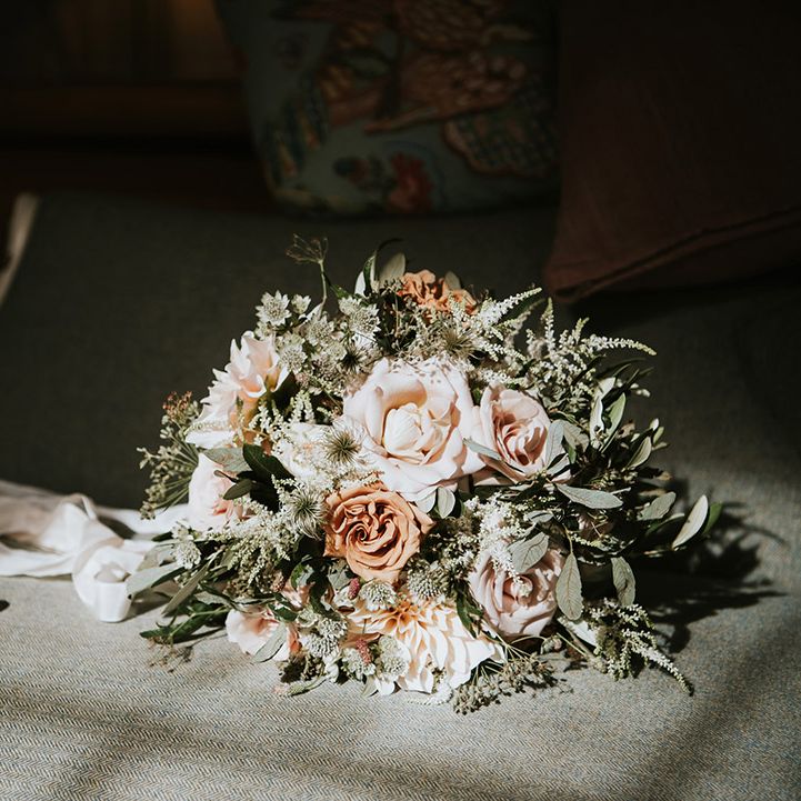 Romantic wedding bouquet tied with ribbon including ink and cafe au latte roses and foliage 