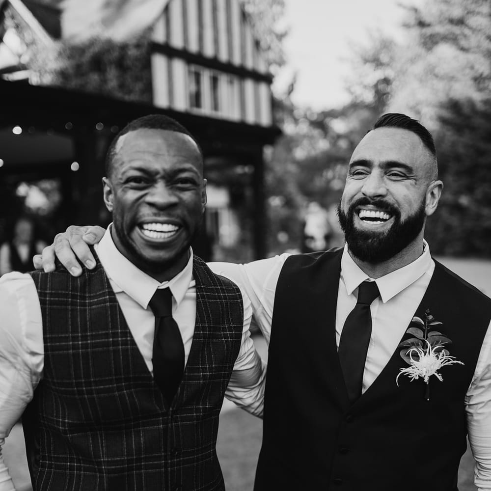 Groom stands with groomsmen as they laugh with one another