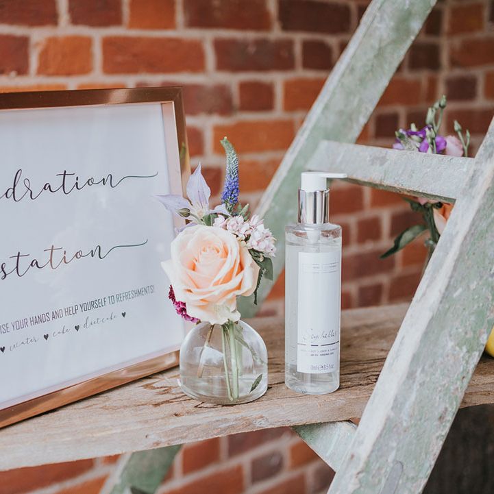Hydration station sign in rose gold frame with flower details and hand sanitiser
