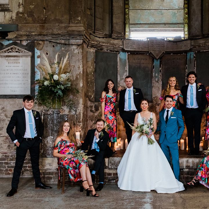 Wedding party inside the Asylum Chapel industrial city wedding venue in bright and colourful outfits 