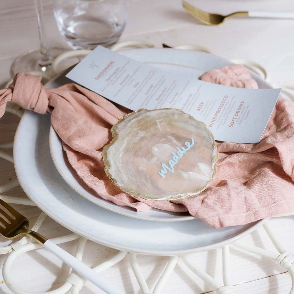 White plates with white and pink wedding stationery menu and name tags on crystal slices